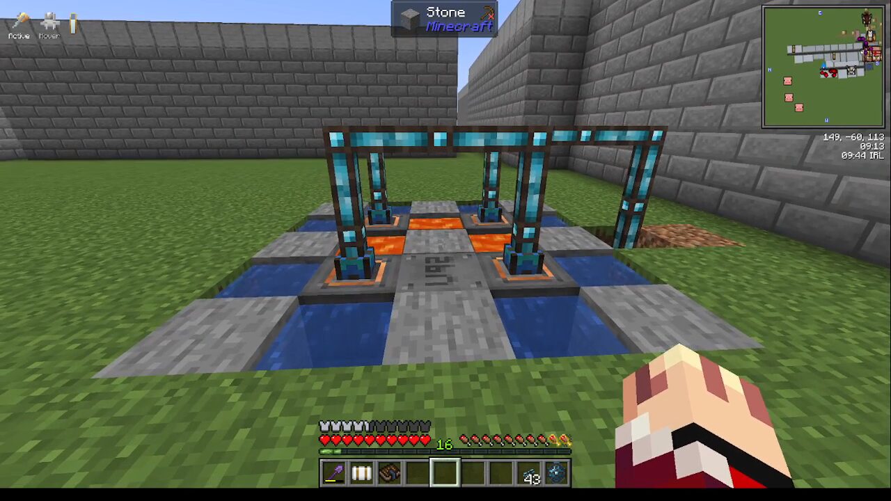 Minecraft screenshot of a compact redstone/tile-based machine with blue glass-encased frames over water channels, set in a walled grassy courtyard; the player's inventory and hand are visible at the bottom right.