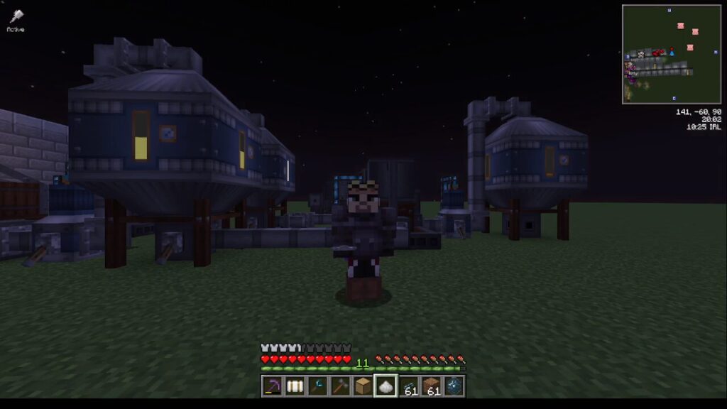 Minecraft character stands on grassy terrain at night with blue modular buildings behind, inventory and health bar visible at bottom.
