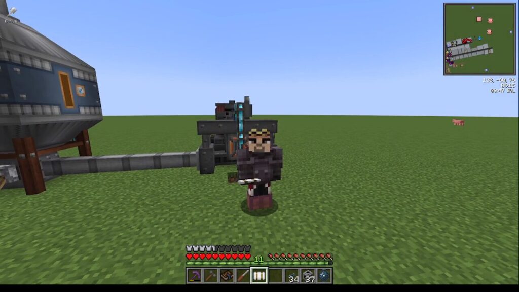 Minecraft player in dark armor holds a pickaxe, standing in front of a large processing machine on a flat grassy world; HUD visible on screen.