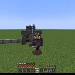 Minecraft player in dark armor holds a pickaxe, standing in front of a large processing machine on a flat grassy world; HUD visible on screen.