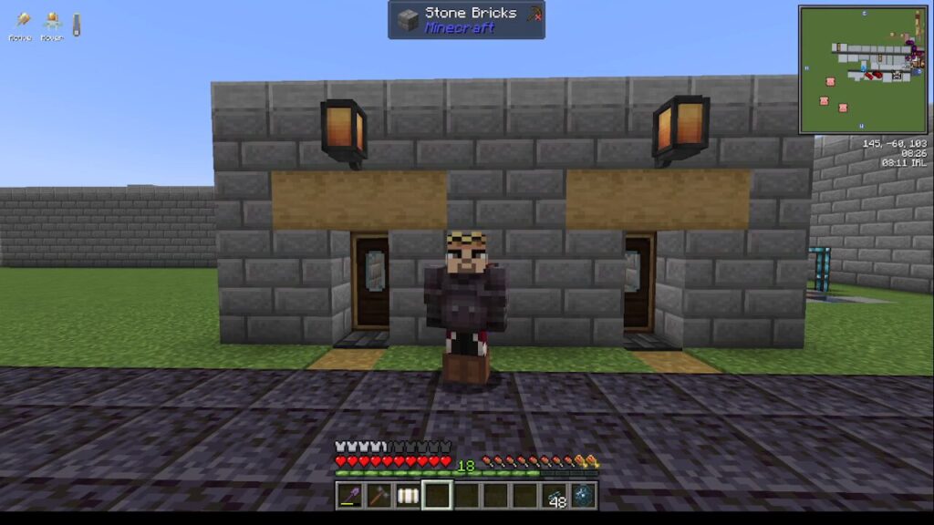 Minecraft screenshot: a player in dark armor stands between two wooden doors in a gray stone-brick building, with lanterns and a paved path.